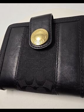 Black Coach trifold wallet featuring signature jacquard fabric with leather trim